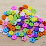 กระดุมพลาสติก รูปดอกไม้ คละสี ขนาด 11 มิล [แพ็ค 30 เม็ด]